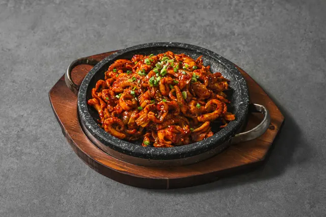 달궈진 돌판 위에 붉은 양념 볶음 요리가 올려진 고봉당 메뉴